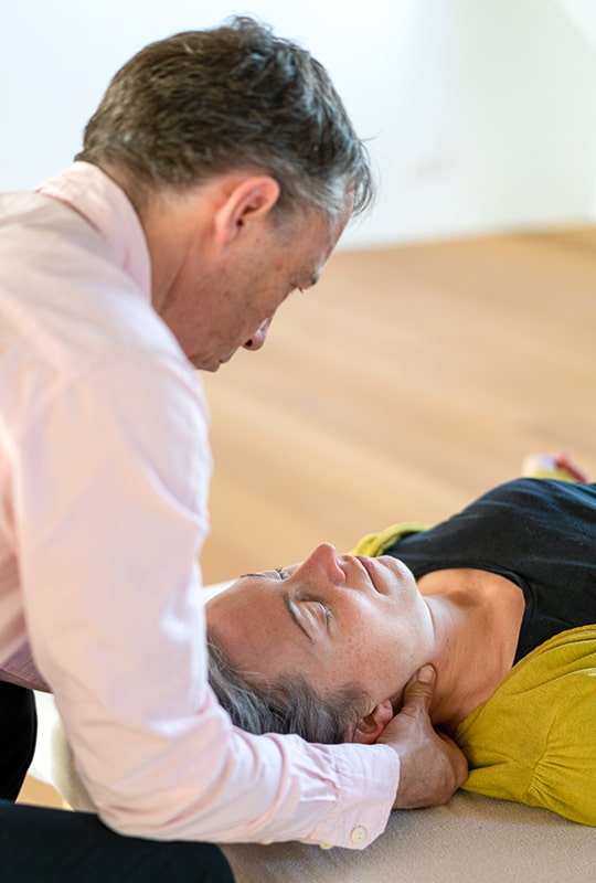 Feldenkrais-Therapeut behandelt auf dem Rücken liegende Patientin