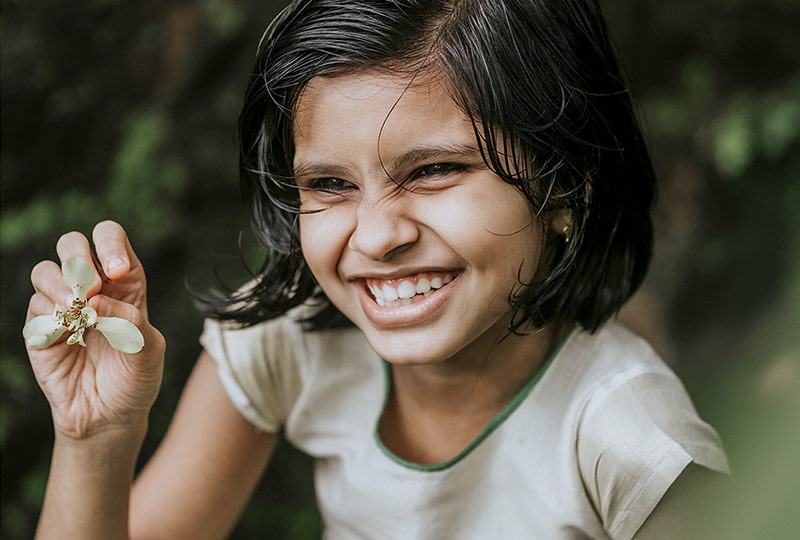 lächelndes Mädchen hält eine Blütenknospe in der Hand