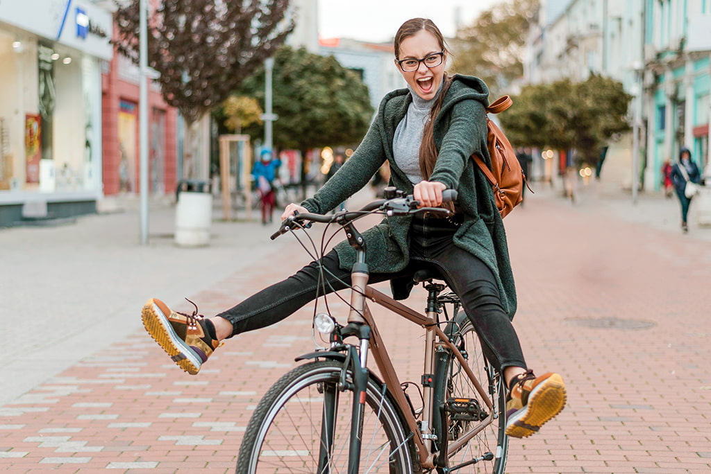 Junge Frau fährt vergnügt auf Fahrrad durch die Innenstadt