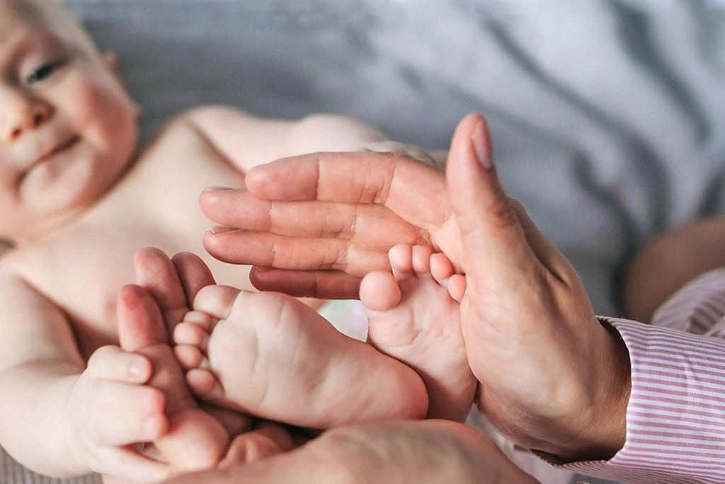Frauenhände massieren sanft Babyfüsse