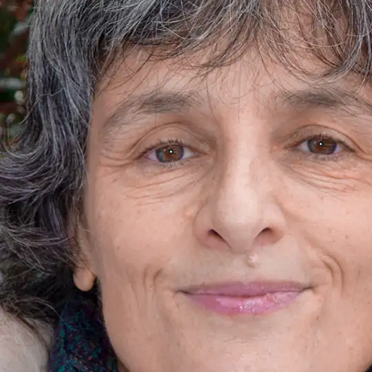 Grossaufnahme auf das Gesicht einer schmunzelnden Dame mit grauem Haar